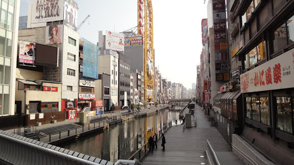 looking down the canal and walkway with buildings on each side.  one of the buildings includes an oval ferris wheel